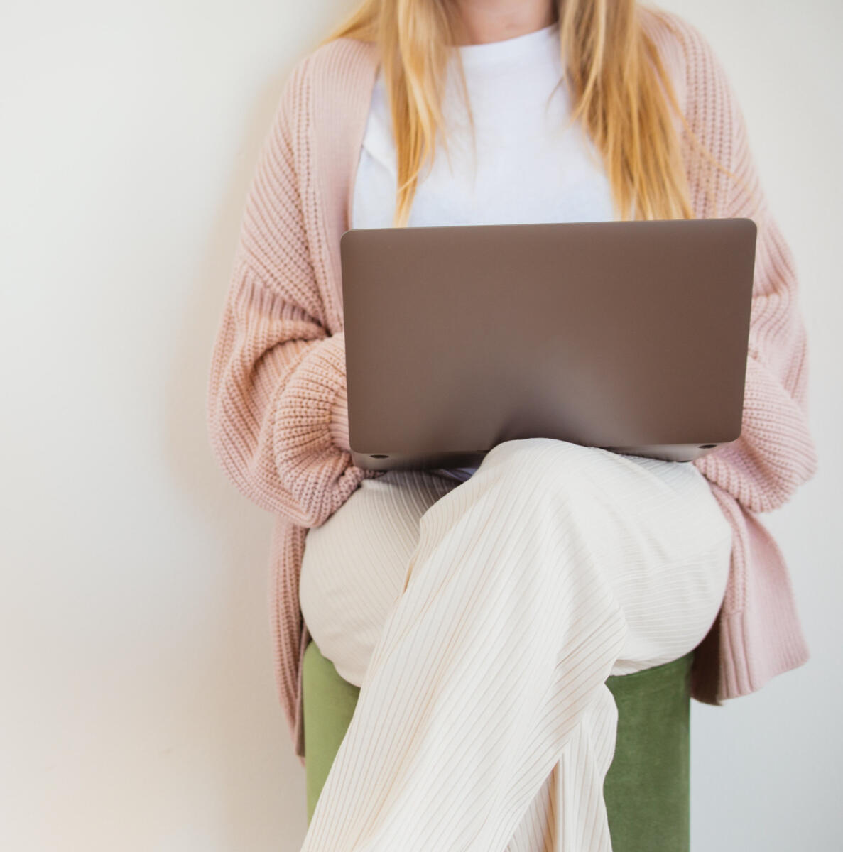Job search help Ontario Career Support for Job Seekers - Woman sitting on a stool, legs crossed, with an open laptop on her lap.